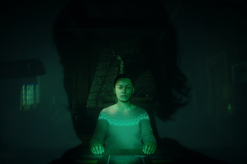 Alan Wake 2: Saga Anderson sat at a desk and bathed in a green glow.